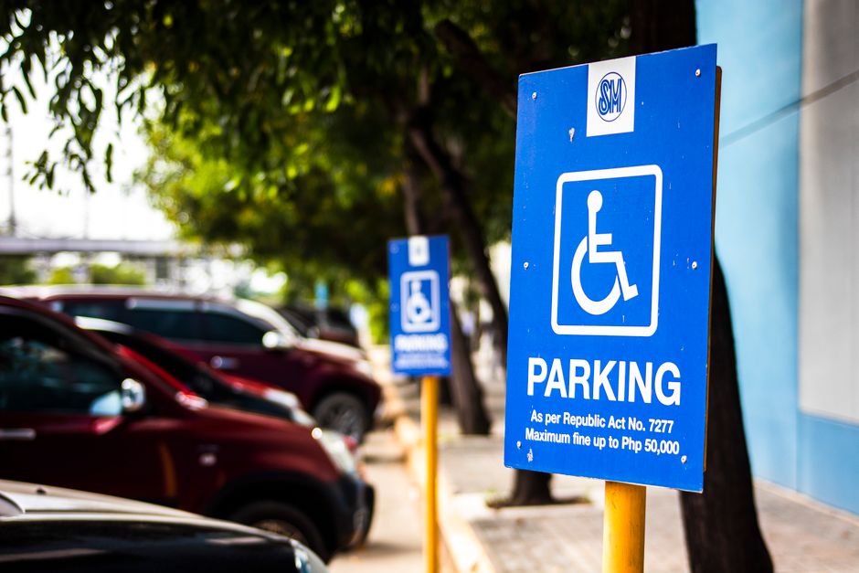 A rectangular white sign with a red border, mounted on a black metal pole, displaying the words 'NO OVERNIGHT PARKING' in bold red capital letters, with a red arrow pointing in both directions beneath